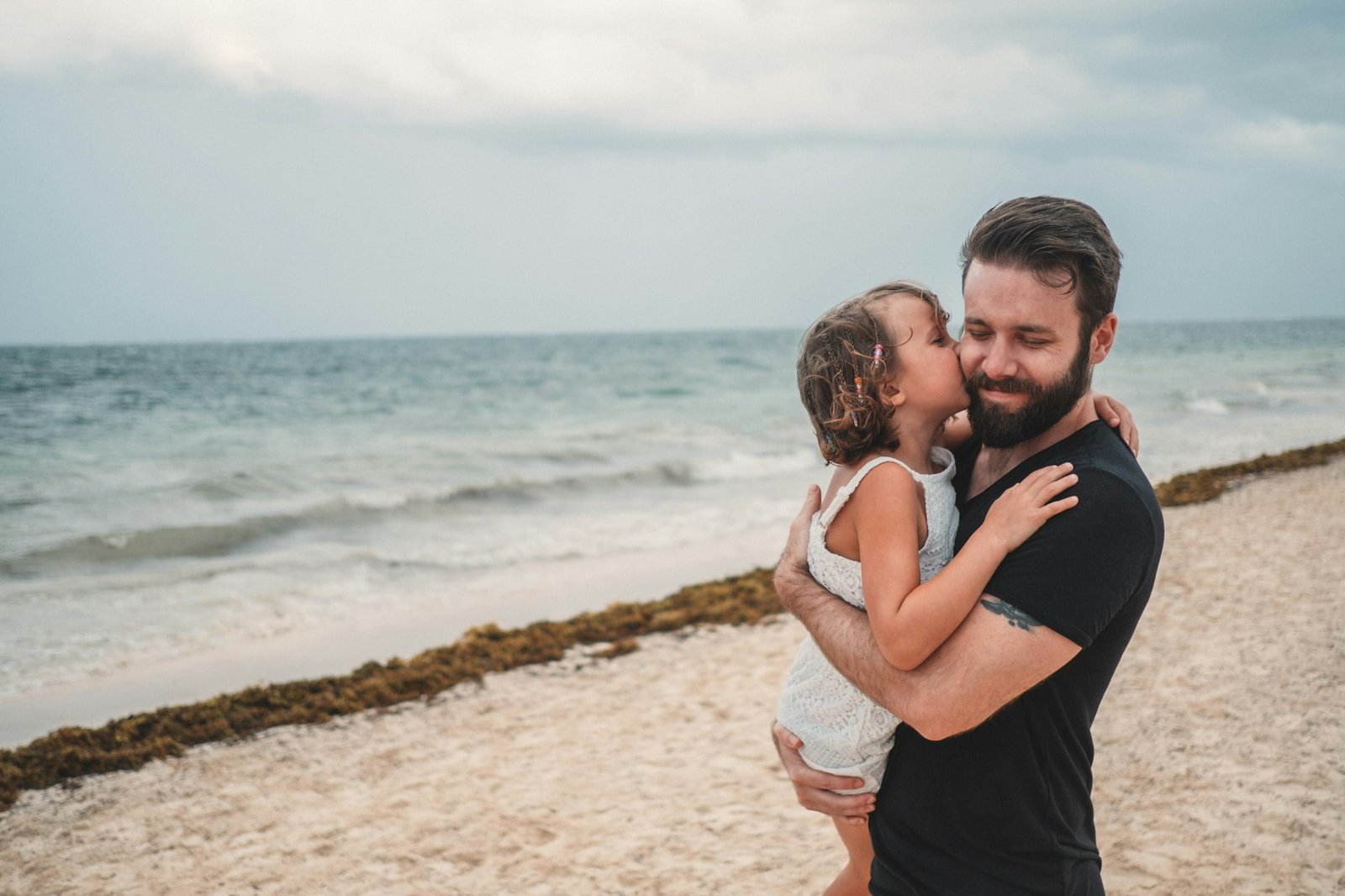 Father kissing daughter on beach, Cancun, Mexico